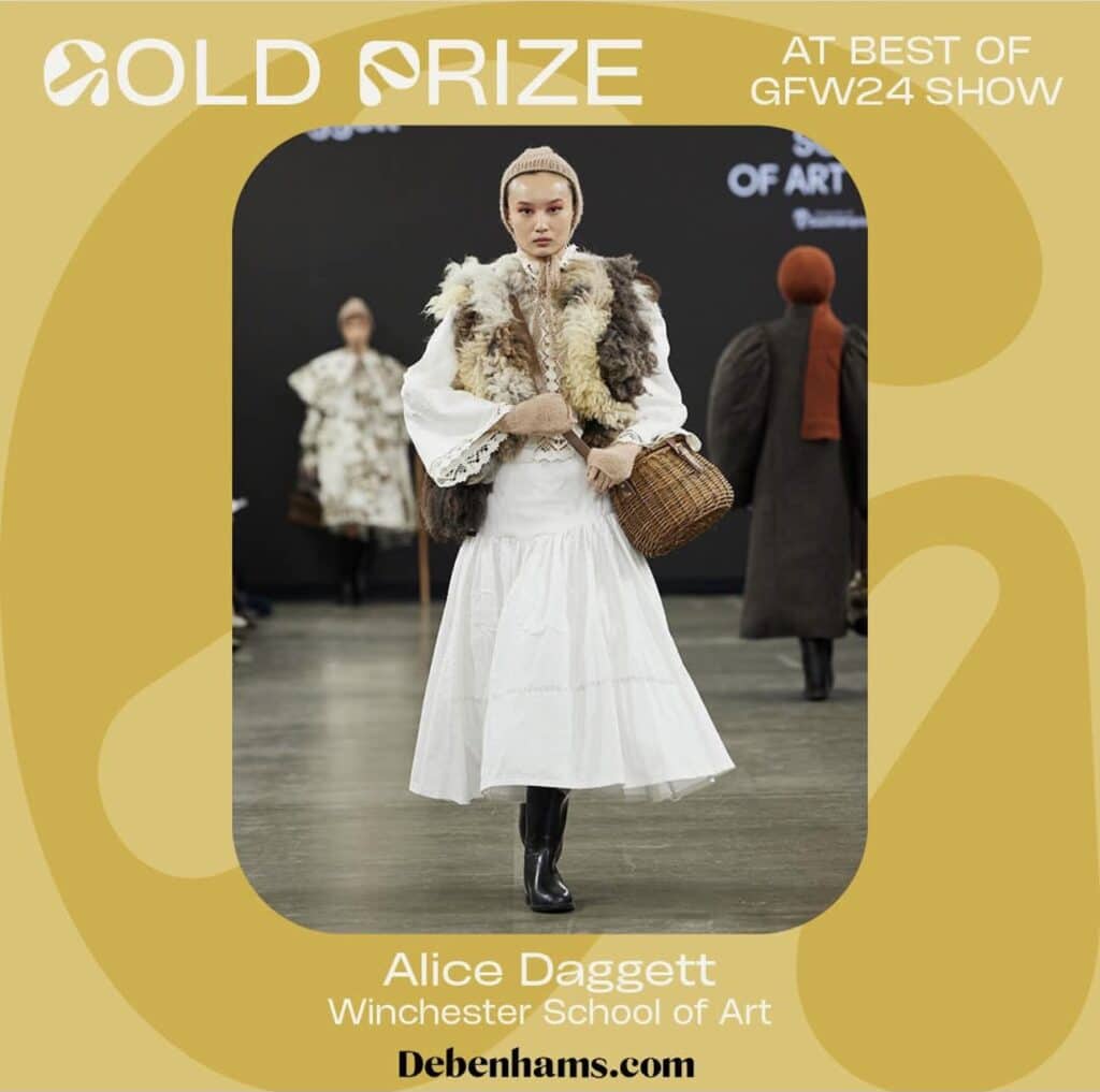 Model wearing a white dress with a fur shawl and black boots, holding a wicker basket on the runway. Text reads "Gold Prize, GFW24 Show, Alice Daggett, Winchester School of Art, Debenhams.com." Discover more trends with our Online Fashion Courses.